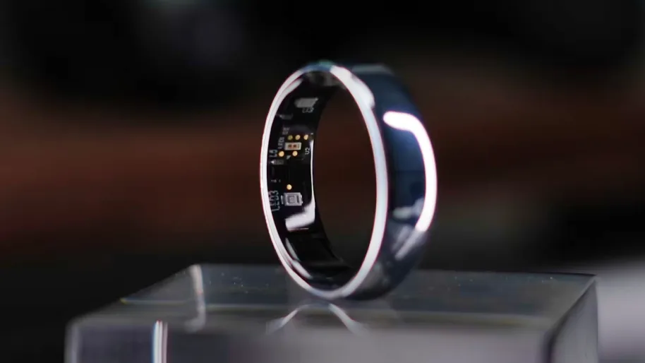 A smart ring on a clear pedestal, the sensor array inside it lit from within.